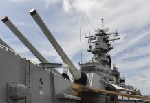 Close-up of a battleships naval guns and superstructure against a cloudy sky