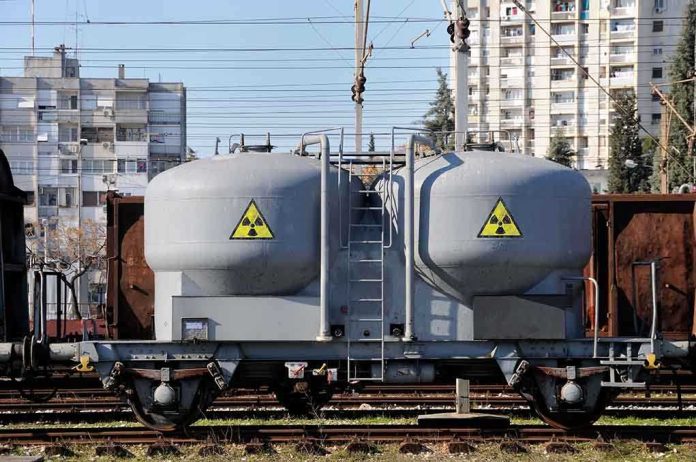 A railway tank car with a nuclear warning symbol parked on tracks near urban buildings