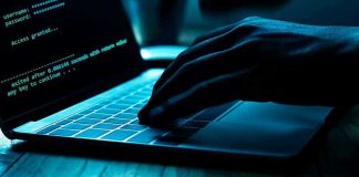 Hand typing on laptop with code on screen.