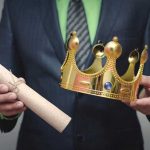 Person holding a crown and a scroll
