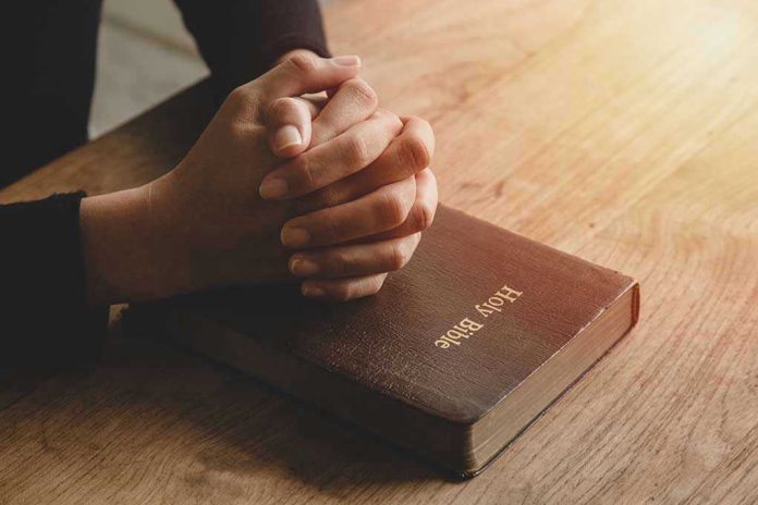 1801756960 Hands praying on a Bible.