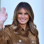 Melania UNLEASHES — Calls Kimmel a Coward Person smiling and waving wearing a brown coat