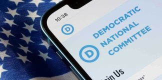 Democrat CAUGHT Posing as Republican Under Oath Phone displaying Democratic National Committee website over flag.