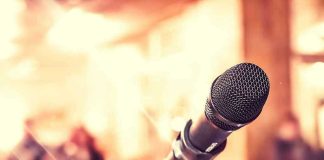 Close-up of microphone with blurred audience background.