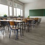 Pro-ICE Flyer Triggers SUSPENSION — Profanity Walks Empty classroom with desks, chairs, windows, and chalkboard.