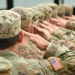 Apache Pilots SUSPENDED — Hegseth’s Stunning Reversal Soldiers in uniform saluting, American flag patch visible.