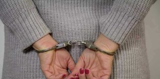 Soldier’s Wife ARRESTED on U.S. Military Base Person in handcuffs with gray sweater.