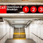 Subway exit sign indicating Downtown and Brooklyn with train numbers 1, 2, and 3