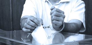 Lawmaker ARRESTED–Chilling Charges MULTIPLY A handcuffed individual placing a ballot into a transparent voting box