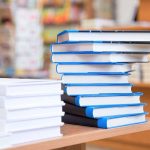 Tennessee Library Chief FIRED Over Books A stack of neatly arranged books on a wooden table in a bookstore