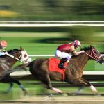 Two jockeys racing on horses at high speed on a track