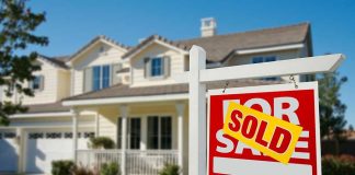 A house with a Sold sign in the front yard