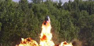 A large explosion with flames and smoke in an outdoor setting