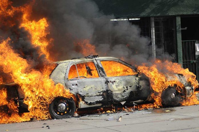 A car engulfed in flames with thick smoke billowing into the air