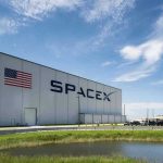 MUSK’S Mega IPO Upends Wall Street SpaceX building with American flag and launch pad.