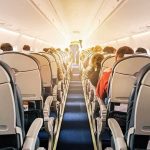 airplane cabin with passengers seated in economy class