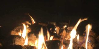 Fire pit flames over lava rocks at night