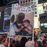 Protesters in Times Square holding a sign and Israeli flags