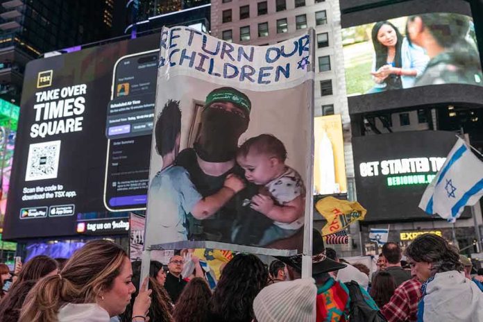 shutterstock_2377492653 Protesters in Times Square holding a sign and Israeli flags