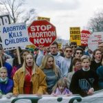 Federal Judge SMACKS Michigan Abortion Rule Protesters holding anti-abortion signs at a rally.
