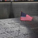 American flag on a rainy memorial nameplate.