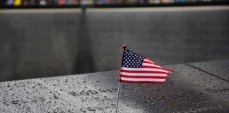 American flag on a rainy memorial nameplate.