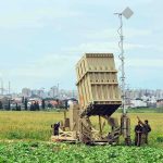 Military defense system deployed in a field with soldiers nearby