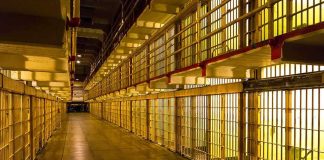 Prison cell block corridor with barred cells and upper walkways