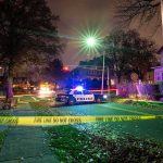 Police car blocks residential street at night behind caution tape