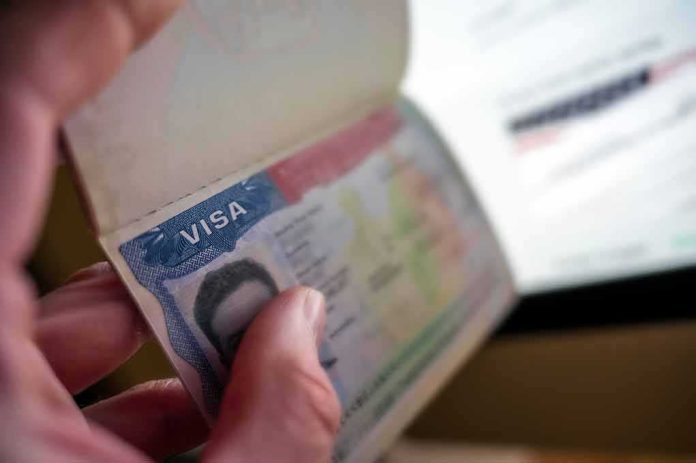 shutterstock_2559918417 Hand holding a passport with a visa page