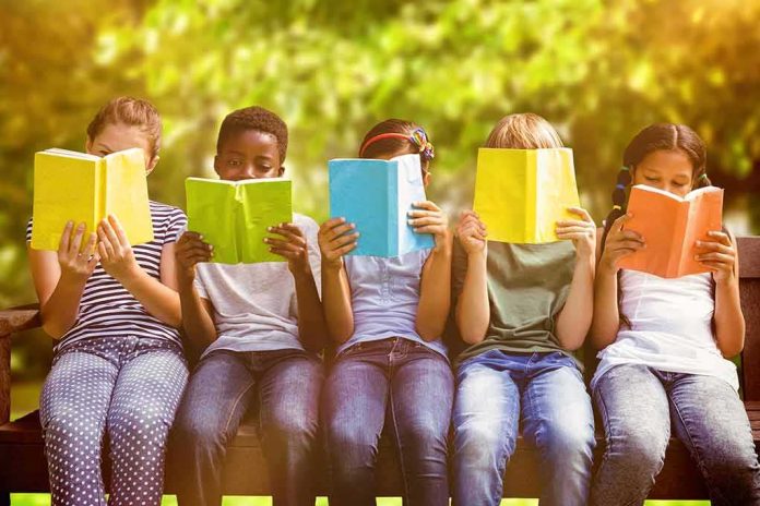 Children sitting on a bench reading colorful books outdoors
