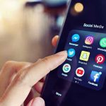 Finger tapping smartphone social media app icons.