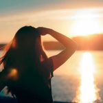 Silhouette of a person looking at a sunset over water