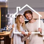 Couple holding a house-shaped frame indoors