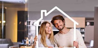 Couple holding a house-shaped frame indoors