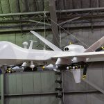 military drone with missiles suspended in a hangar