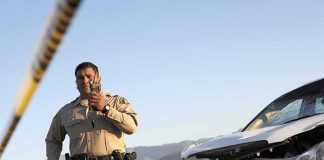 Police officer at crash scene near damaged white car
