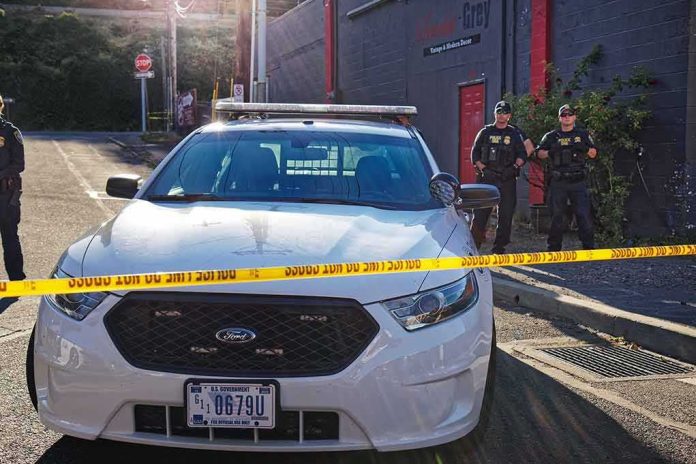 shutterstock_1143336623 Police car behind yellow caution tape on a city street