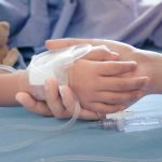 Child's hand with IV line held by another hand