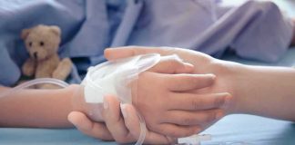 Child's hand with IV line held by another hand
