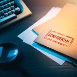 Confidential file folder on desk with magnifying glass and typewriter