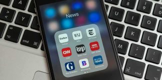 Smartphone displaying a folder of news apps on a laptop keyboard