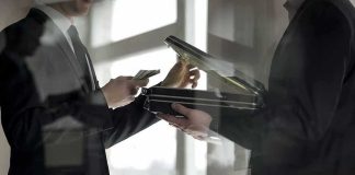Two men in suits exchanging cash and a briefcase