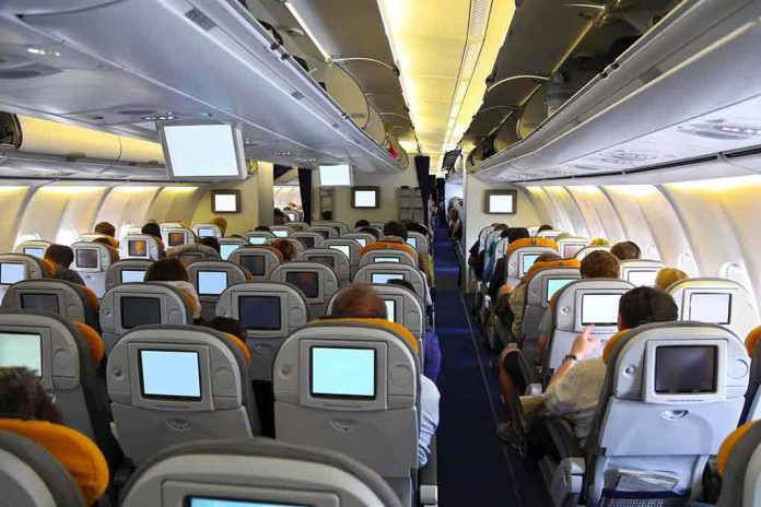 Interior view of an airplane with passengers seated and using in-flight entertainment screens
