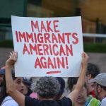 Riot Gear, Fireworks — Then This Move Teddy Williams at a protest holding a sign reading 'Make Immigrants American Again'