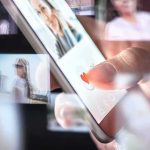 Hand tapping heart icon on smartphone screen
