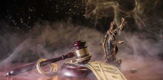 Judge's gavel with handcuffs and cash on a smoky table