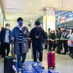 Akira Fukuzawa among masked travelers at a busy train station