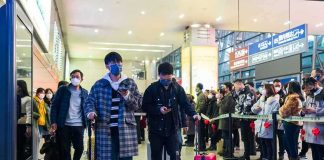 Akira Fukuzawa among masked travelers at a busy train station