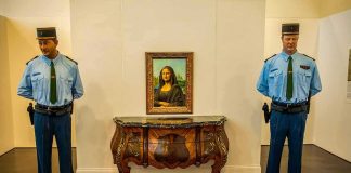 Two uniformed guards flanking a framed portrait on a wall